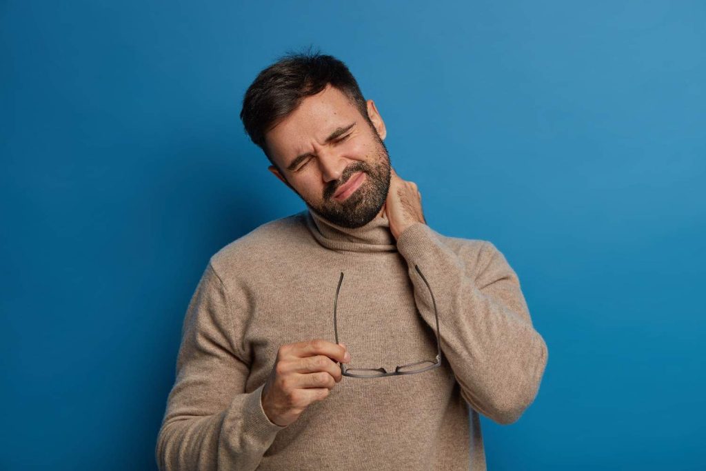 Person gently stretching their neck to relieve stiffness while learning whether cracking your neck is safe.