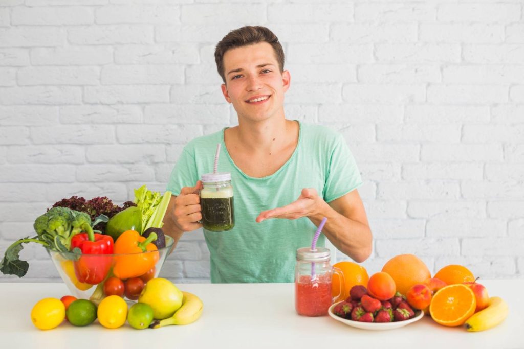 Man holding a green smoothie with fruits and vegetables that support healthy blood circulation