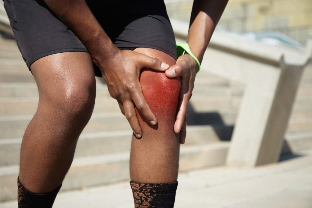 Person experiencing gout in knee with swollen red and painful knee joint