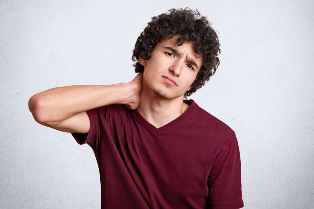 Man experiencing neck pain that may spread toward the collarbone